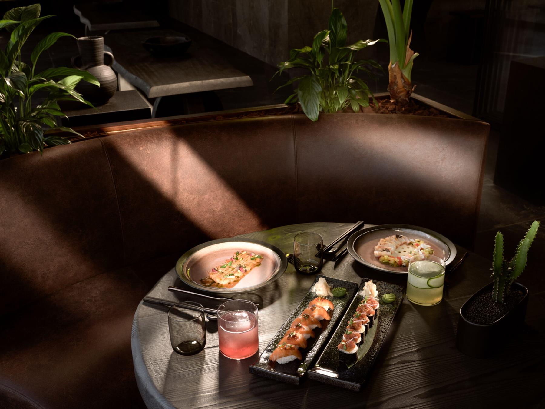 Umi Nikkei restaurant at Acro Suites, sushi and Nikkei plates on a dark timber table in low evening light
