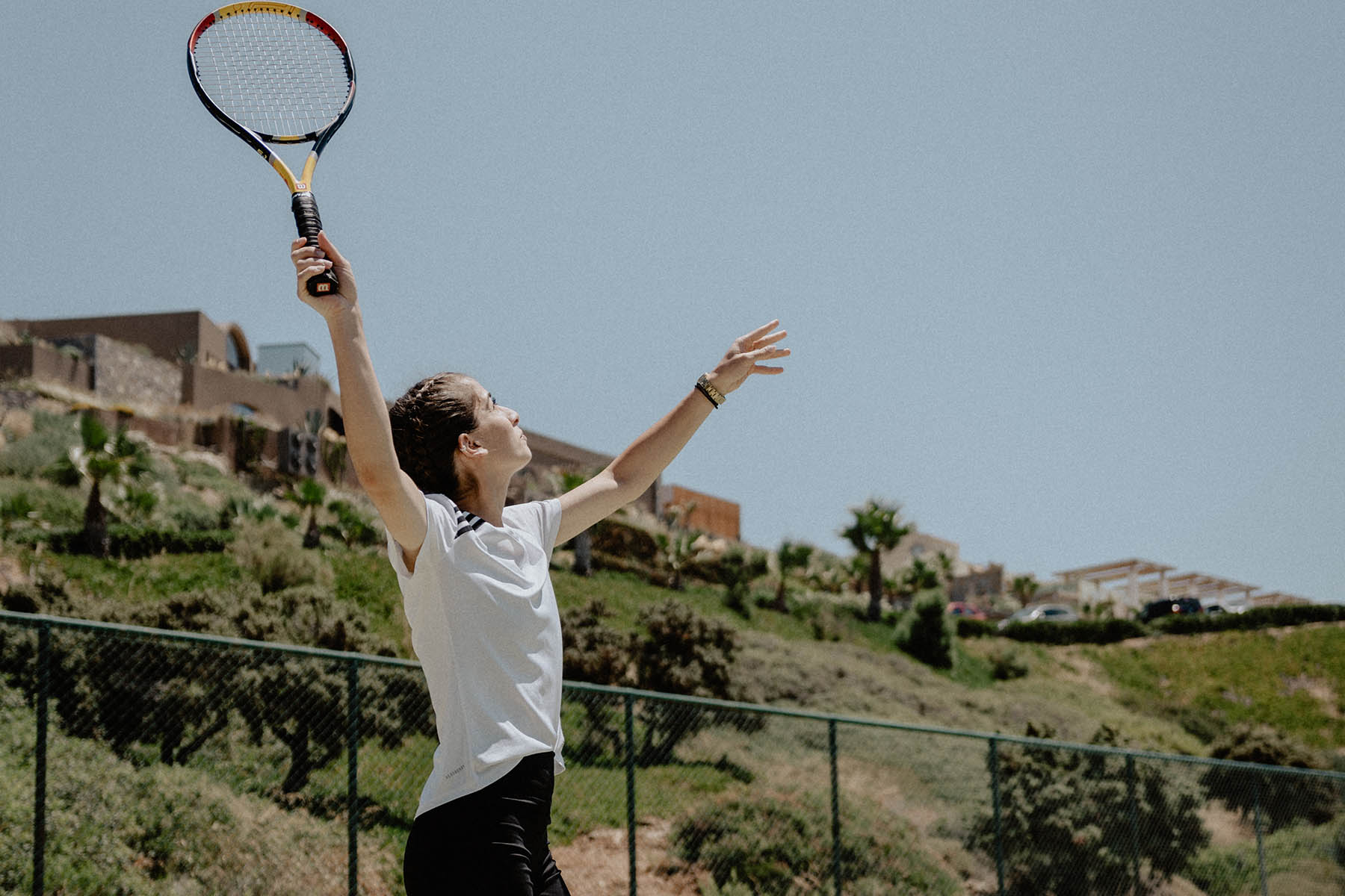 A player serving on the Racquet Club courts above the hillside