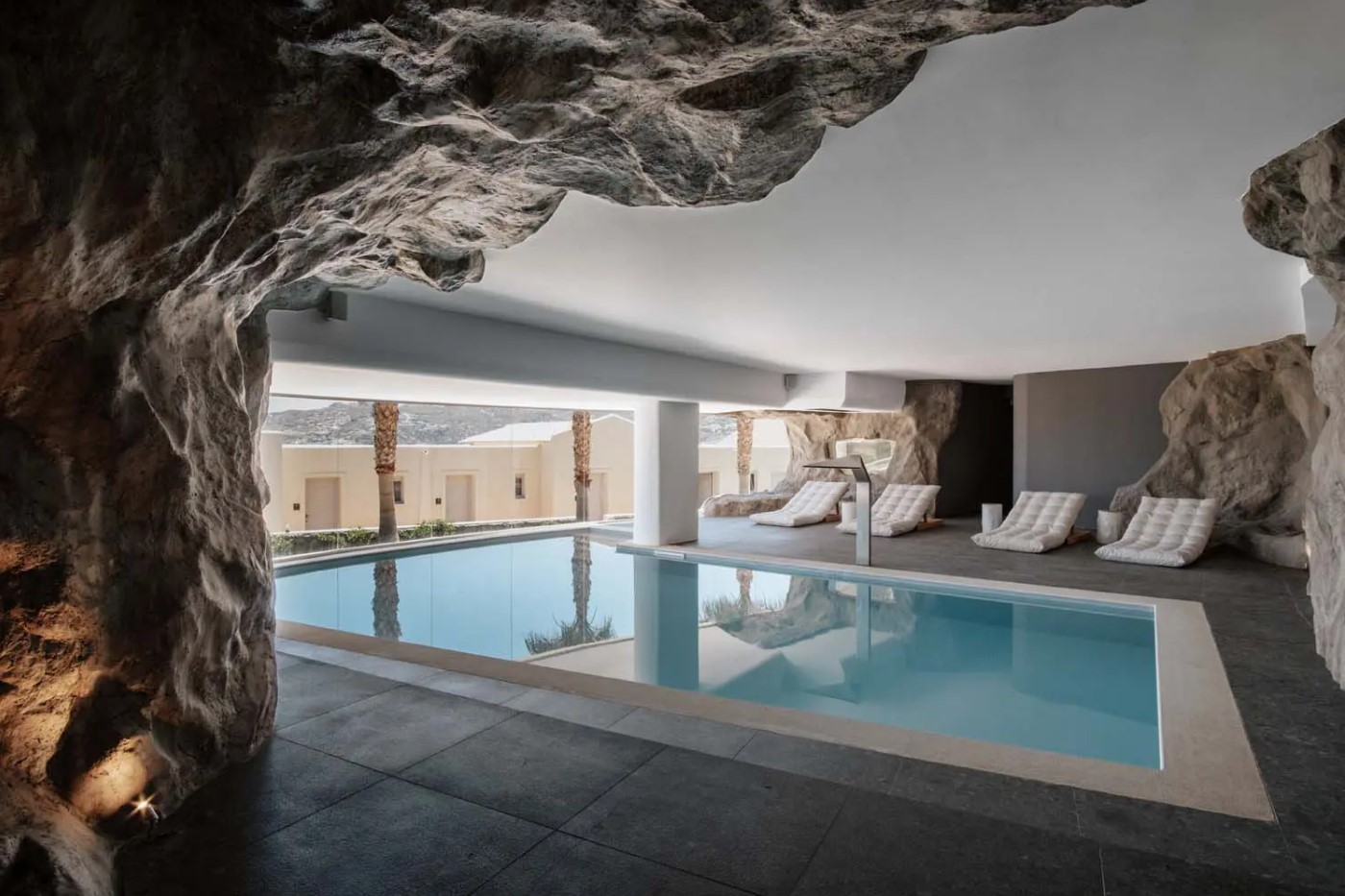 The heated cave pool of the Sea Cave Spa, rock walls framing loungers and still water