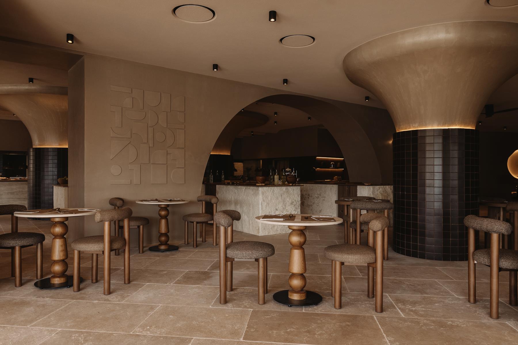 The Veranda restaurant, sculpted arches, dark tiled columns and wooden tables set for dinner